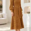 Warm amber crocheted midi dress with honeycomb waffle texture, ribbed cuffs, matching belt sash, and scalloped hem worn with heels