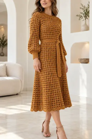 Warm amber crocheted midi dress with honeycomb waffle texture, ribbed cuffs, matching belt sash, and scalloped hem worn with heels