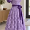 Lilac crochet lattice dress with puff sleeves and violet ribbon belt displayed on white mannequin