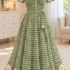 Sage green filet crochet dress on mannequin with cream daisy appliqués around the hem and short sleeves