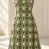 Sage green crochet floral dress with cream flower centers displayed on white mannequin showing A-line silhouette and lattice construction